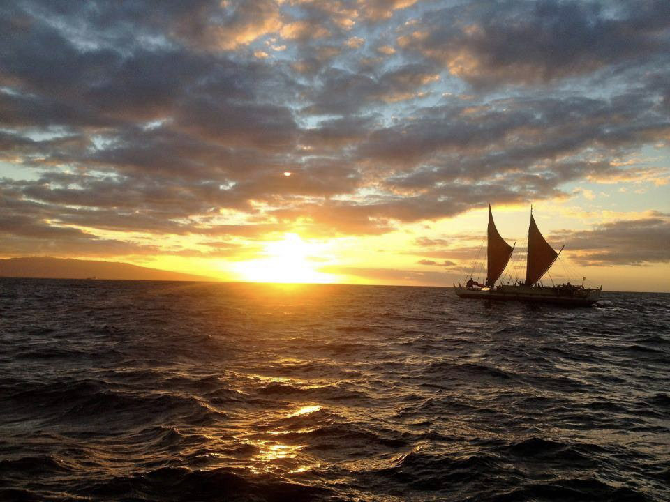 Polynesian voyaging canoe sailing at sunset