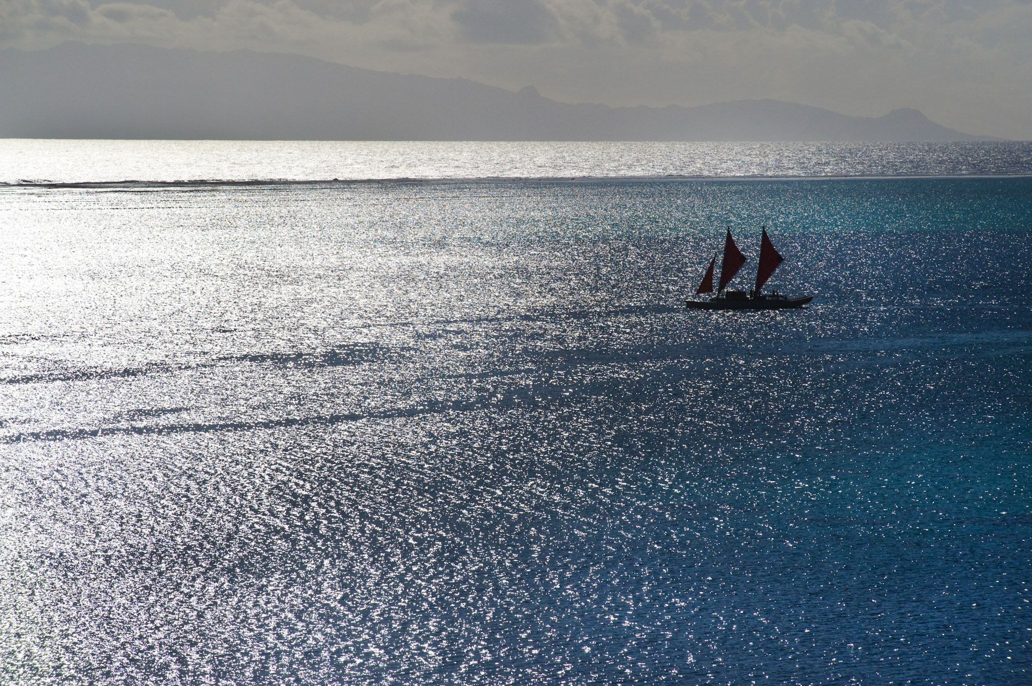 A lone Polynesian voyaging canoe on the open ocean